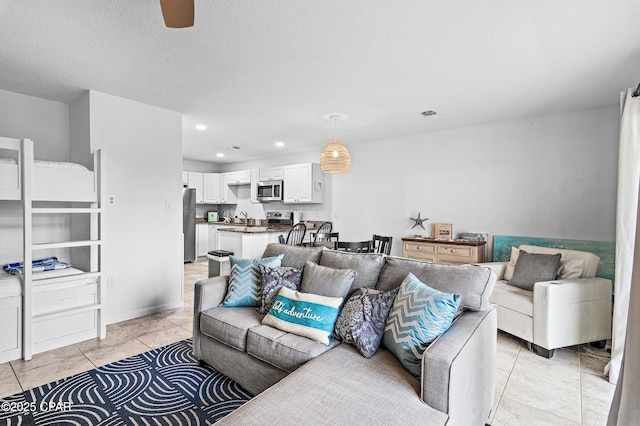 tiled living room featuring a textured ceiling, ceiling fan, and sink