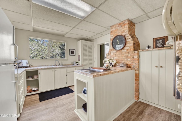 kitchen featuring light hardwood / wood-style floors, white cabinetry, white refrigerator, and a paneled ceiling