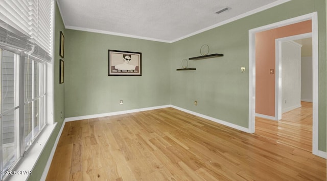 spare room with ornamental molding and light hardwood / wood-style floors