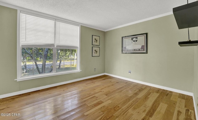 spare room featuring light wood-type flooring, crown molding, and a textured ceiling