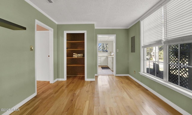 interior space featuring a textured ceiling, ornamental molding, and light hardwood / wood-style flooring