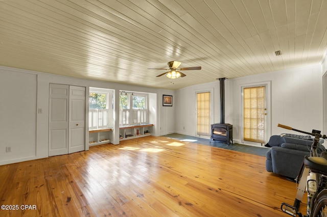 unfurnished living room with wooden ceiling, a wood stove, hardwood / wood-style floors, and ceiling fan