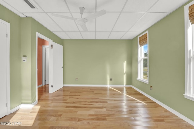 unfurnished room featuring ceiling fan, a drop ceiling, and light hardwood / wood-style flooring