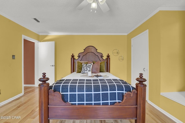 bedroom with ceiling fan, wood-type flooring, ornamental molding, and a textured ceiling