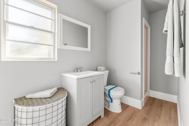 bathroom with hardwood / wood-style floors, vanity, toilet, and walk in shower