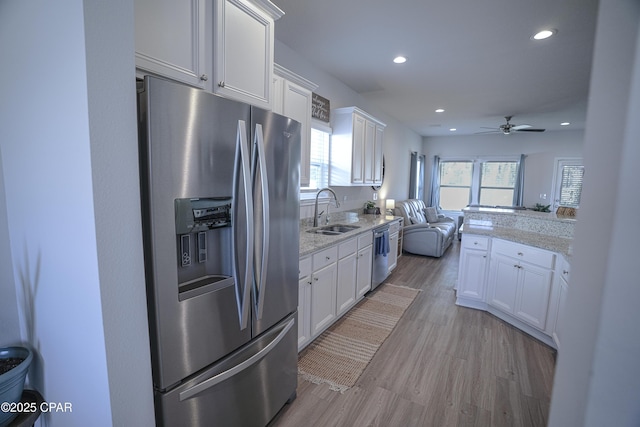 kitchen featuring white cabinetry, sink, light hardwood / wood-style floors, and appliances with stainless steel finishes