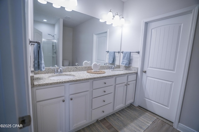 bathroom featuring toilet, vanity, hardwood / wood-style floors, and walk in shower