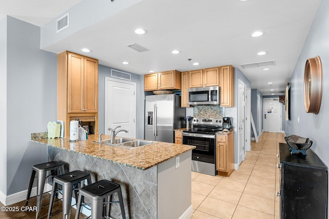 kitchen featuring visible vents, a peninsula, a sink, stainless steel appliances, and backsplash