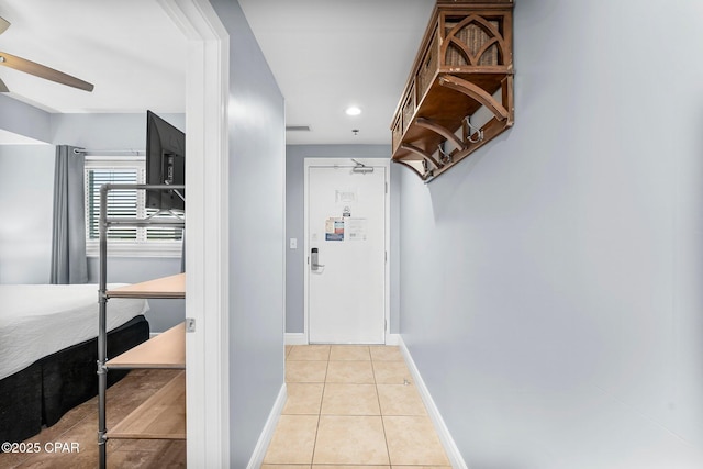 hall with light tile patterned flooring, visible vents, and baseboards