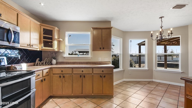 kitchen featuring visible vents, stainless steel appliances, light countertops, and glass insert cabinets