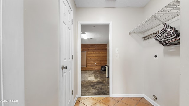 laundry room featuring laundry area, light tile patterned flooring, electric dryer hookup, and baseboards