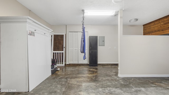 garage featuring electric panel and baseboards