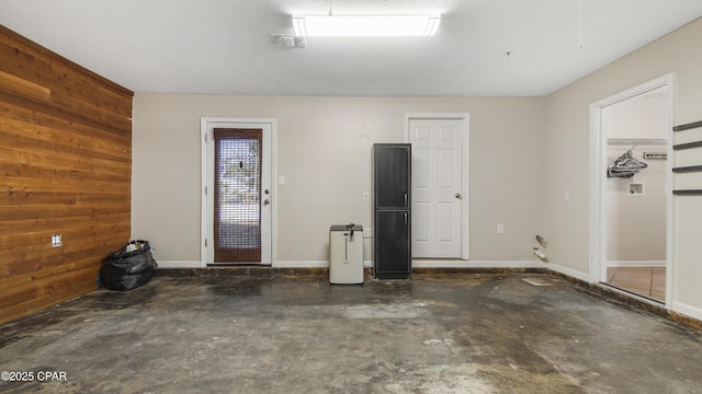 garage featuring visible vents, wood walls, and baseboards