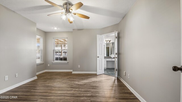 unfurnished bedroom featuring ceiling fan, ensuite bathroom, and dark hardwood / wood-style floors