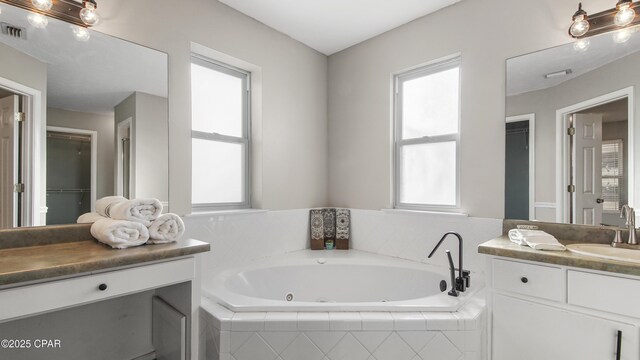 bathroom with vanity and tiled bath