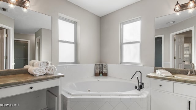 bathroom featuring a wealth of natural light, a jetted tub, and vanity