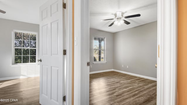 empty room featuring dark wood finished floors, baseboards, and ceiling fan