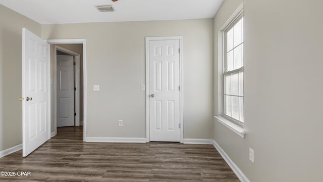 unfurnished bedroom with dark wood finished floors, visible vents, and baseboards