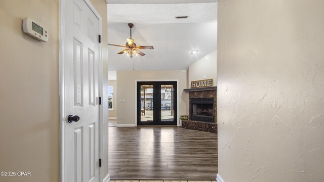 unfurnished living room with ceiling fan, french doors, a premium fireplace, lofted ceiling, and hardwood / wood-style flooring