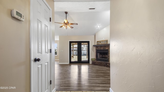 foyer featuring a premium fireplace, wood finished floors, visible vents, a ceiling fan, and french doors