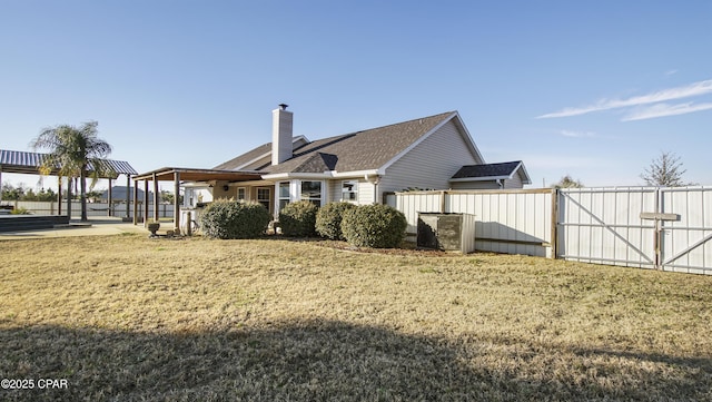 view of side of home with a chimney, a gate, fence, and a lawn