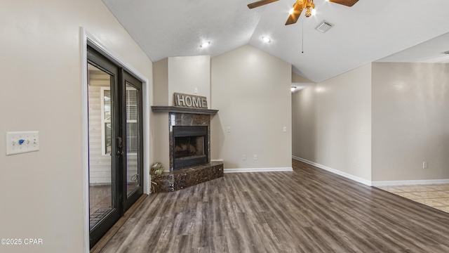 unfurnished living room with french doors, vaulted ceiling, hardwood / wood-style flooring, ceiling fan, and a premium fireplace