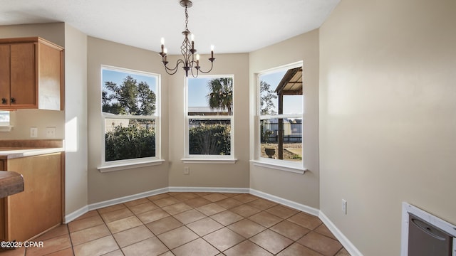 unfurnished dining area featuring light tile patterned flooring, a wealth of natural light, and an inviting chandelier