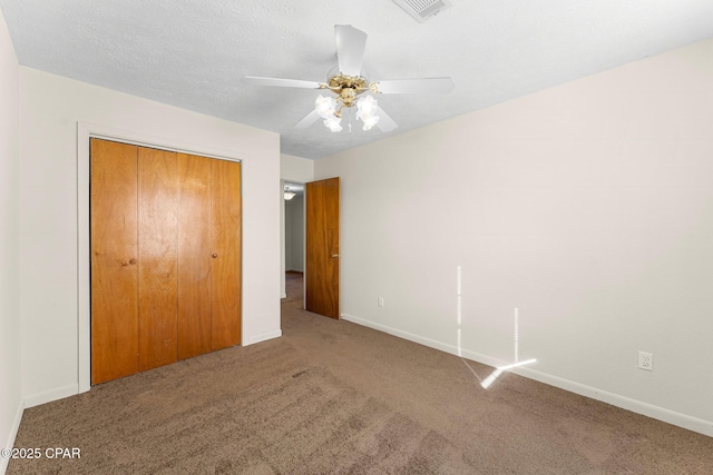 unfurnished bedroom with ceiling fan, carpet, a textured ceiling, and a closet