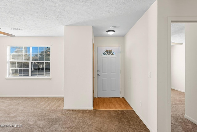 entrance foyer featuring light colored carpet and a textured ceiling