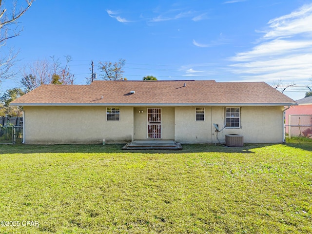 back of house featuring central AC unit and a lawn