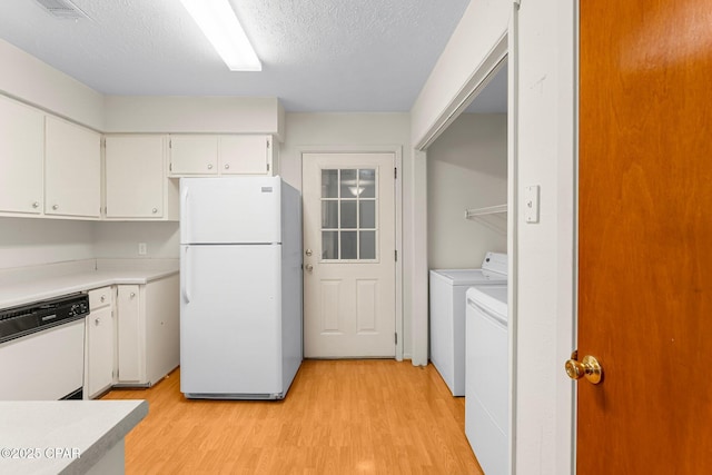 kitchen with white appliances, light hardwood / wood-style flooring, washing machine and clothes dryer, white cabinets, and a textured ceiling