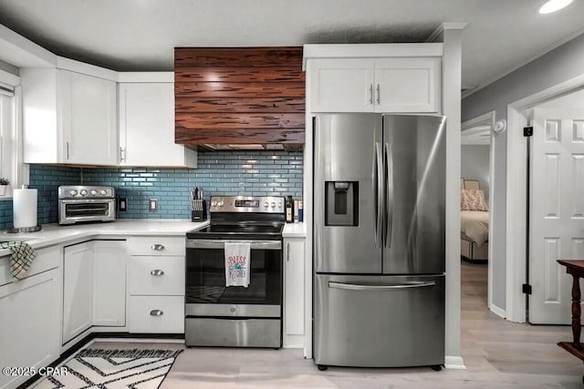 kitchen featuring decorative backsplash, custom exhaust hood, stainless steel appliances, white cabinets, and light hardwood / wood-style floors