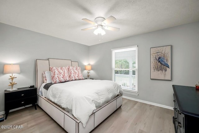 bedroom featuring ceiling fan, light hardwood / wood-style floors, and a textured ceiling