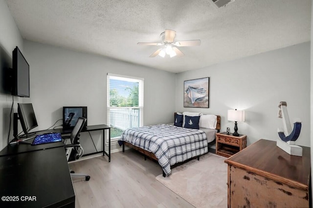 bedroom with a textured ceiling, light hardwood / wood-style flooring, and ceiling fan