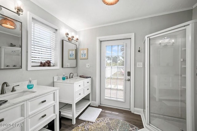 bathroom featuring vanity, wood-type flooring, a shower with shower door, and ornamental molding