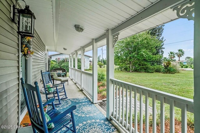 wooden terrace featuring a porch and a yard