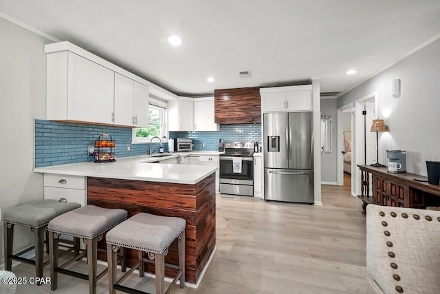 kitchen featuring white cabinetry, backsplash, light hardwood / wood-style floors, a breakfast bar, and appliances with stainless steel finishes