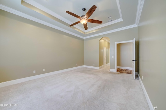 spare room with crown molding, light colored carpet, a tray ceiling, and ceiling fan