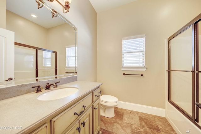 full bathroom featuring vanity, shower / bath combination with glass door, and toilet