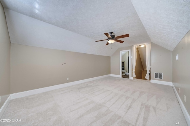 bonus room with lofted ceiling, light carpet, and a textured ceiling