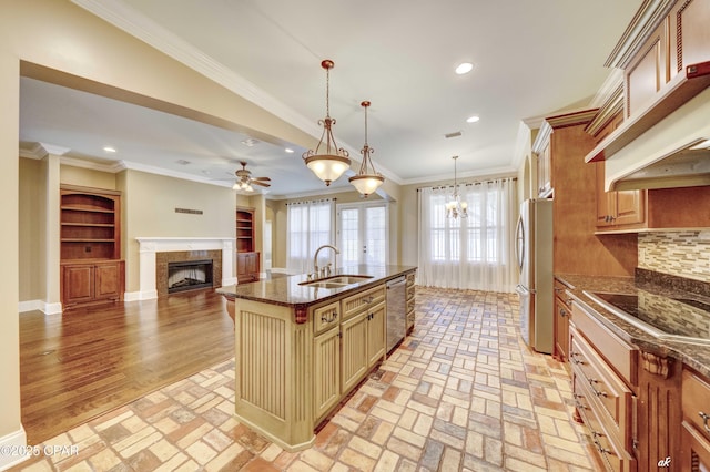 kitchen with a breakfast bar, pendant lighting, an island with sink, sink, and stainless steel appliances