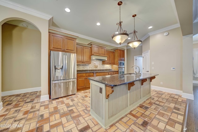 kitchen with sink, appliances with stainless steel finishes, an island with sink, a kitchen bar, and dark stone counters