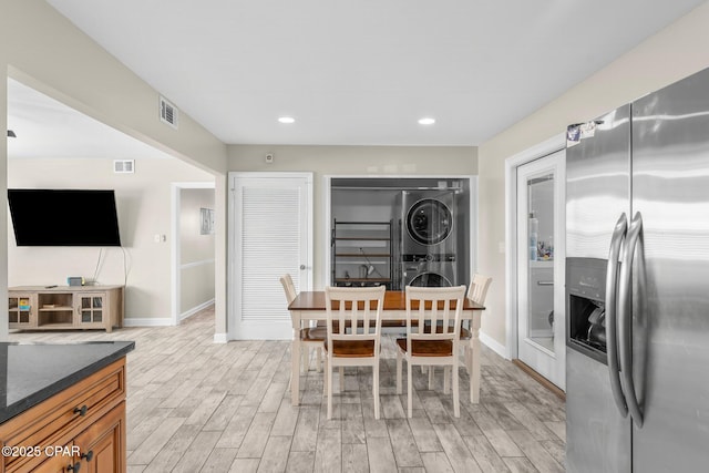 dining area featuring stacked washer and dryer and light hardwood / wood-style flooring