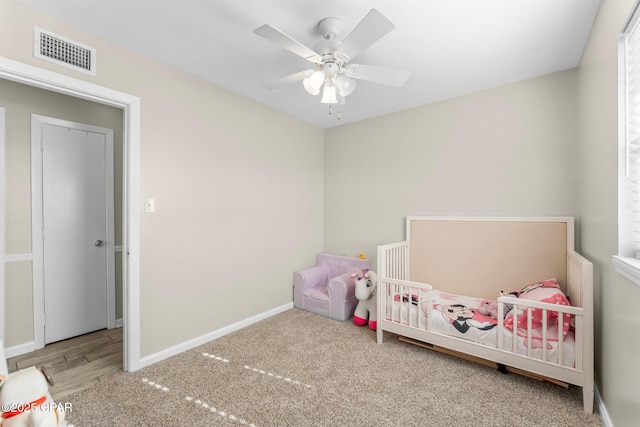 unfurnished bedroom featuring carpet floors, a crib, and ceiling fan