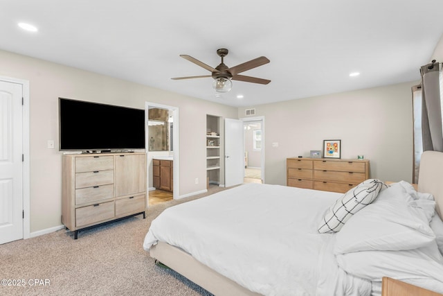 bedroom featuring light carpet, ensuite bath, and ceiling fan