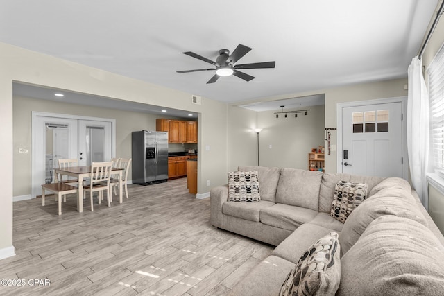 living room with a wealth of natural light, french doors, ceiling fan, and light wood-type flooring