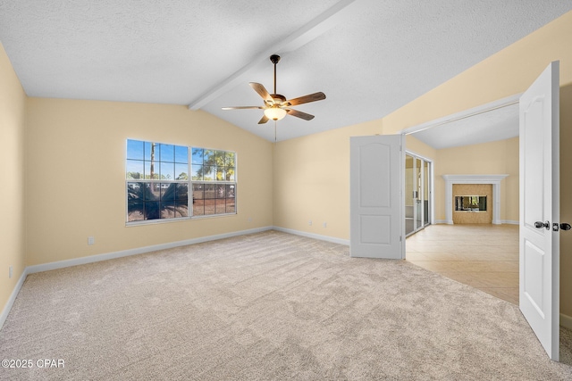 carpeted empty room featuring vaulted ceiling with beams, ceiling fan, and a textured ceiling