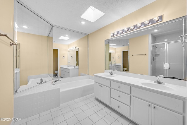 full bathroom featuring a skylight, vanity, a textured ceiling, tile patterned flooring, and toilet