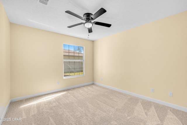 spare room featuring light carpet, ceiling fan, and a textured ceiling