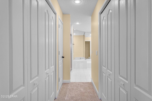 corridor with light colored carpet and a textured ceiling